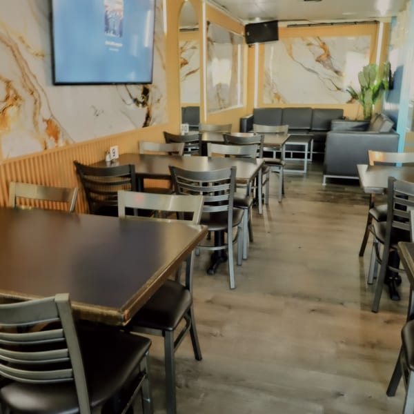 Interior of Island Grill AZ with dining tables, chairs, and a lounge area with marble-patterned walls.