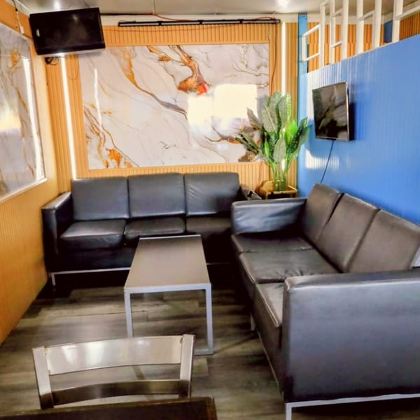 Lounge area with black leather sofas, a coffee table, and a blue accent wall at Island Grill AZ.