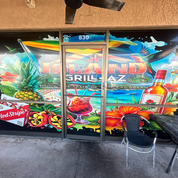 Vibrant Jamaican-themed mural on the Island Grill AZ storefront, featuring tropical drinks, fruit, and hummingbirds.