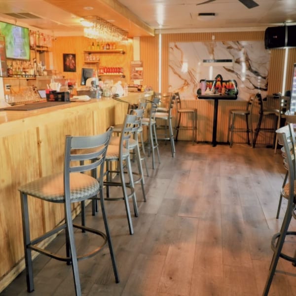 Interior of Island Grill AZ, featuring a long wooden bar with stools and a small table.