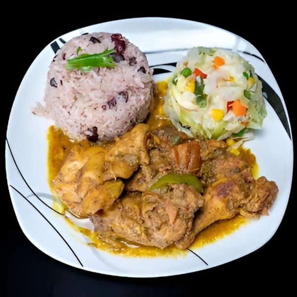 Curried chicken with rice and peas, and mixed vegetables on a white plate.