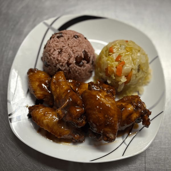 Island Grill AZ jerk chicken wings with rice and peas, and steamed cabbage on a white plate.