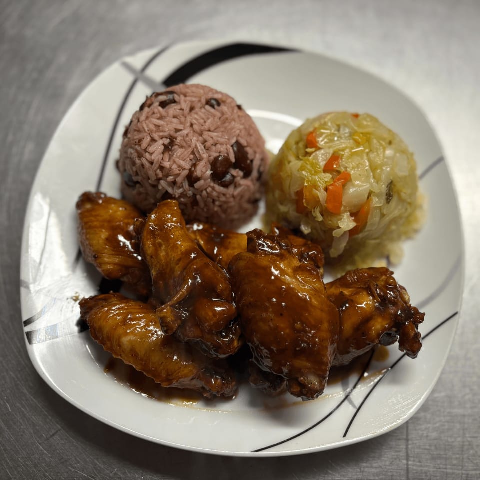Island Grill AZ jerk chicken wings with rice and peas, and steamed cabbage on a white plate.