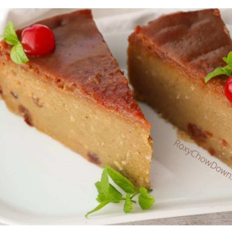 Two slices of Jamaican sweet potato pudding, garnished with a cherry and mint leaves.