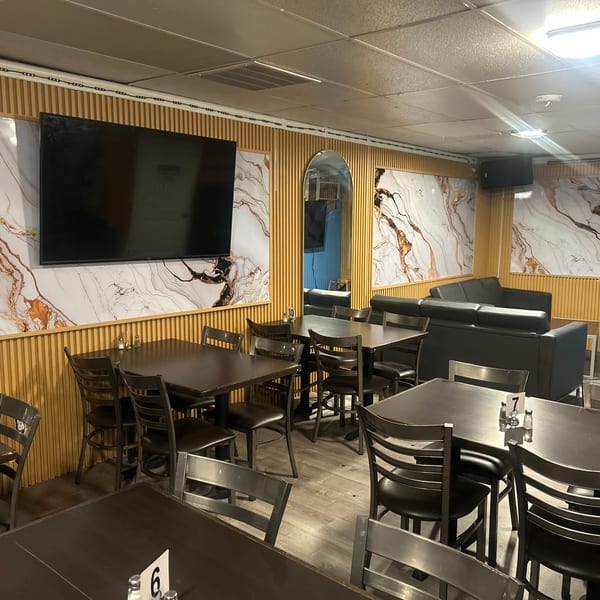 Interior of Island Grill AZ, featuring dining tables, chairs, and a lounge area with a sofa.